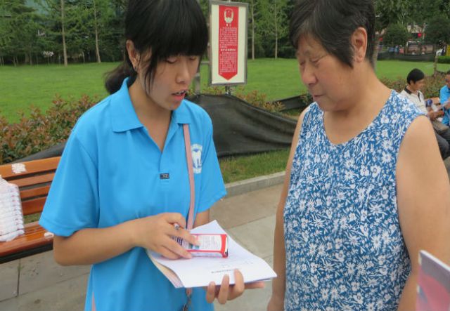 实践队员张敬轩給跳广场舞大妈做问卷调查。